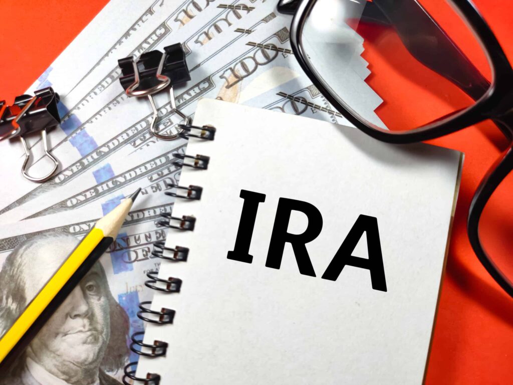 business concept text ira with glasses banknote paper clips red background scaled